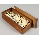 A SET OF EBONY AND BONE DOMINOES and a case. 1.25ins long.
