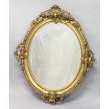 A GOOD 19TH CENTURY GILT FRAMED OVAL MIRROR, the heavy moulded frame applied with four pierced,