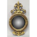 A REGENCY CONVEX GILTWOOD MIRROR, with Fleur de Lys cresting, a moulded frame with carved decoration