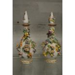 A pair of floral encrusted bottles with stoppers.