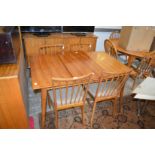 A mid century walnut extending dining table with one leaf together with four matching stick back