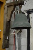 A bronze bell on an old oak bracket.