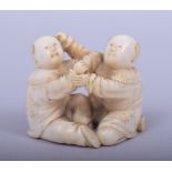 A JAPANESE MEIJI PERIOD CARVED IVORY NETSUKE - KARAKO, the two boys seated whilst playing, one