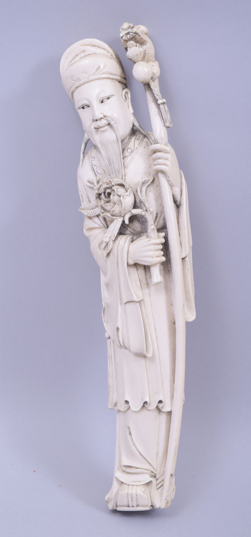 A CHINESE CARVED IVORY FIGURE OF A SAGE, holding a dragon staff, red seal to reverse, 30cm high.