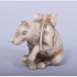 A JAPANESE MEIJI PERIOD CARVED IVORY NETSUKE - KITSUNE, the fox in a seated position with a drum on