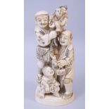 A JAPANESE MEIJI PERIOD CARVED IVORY OKIMONO, depicting two men and a boy holding another figure