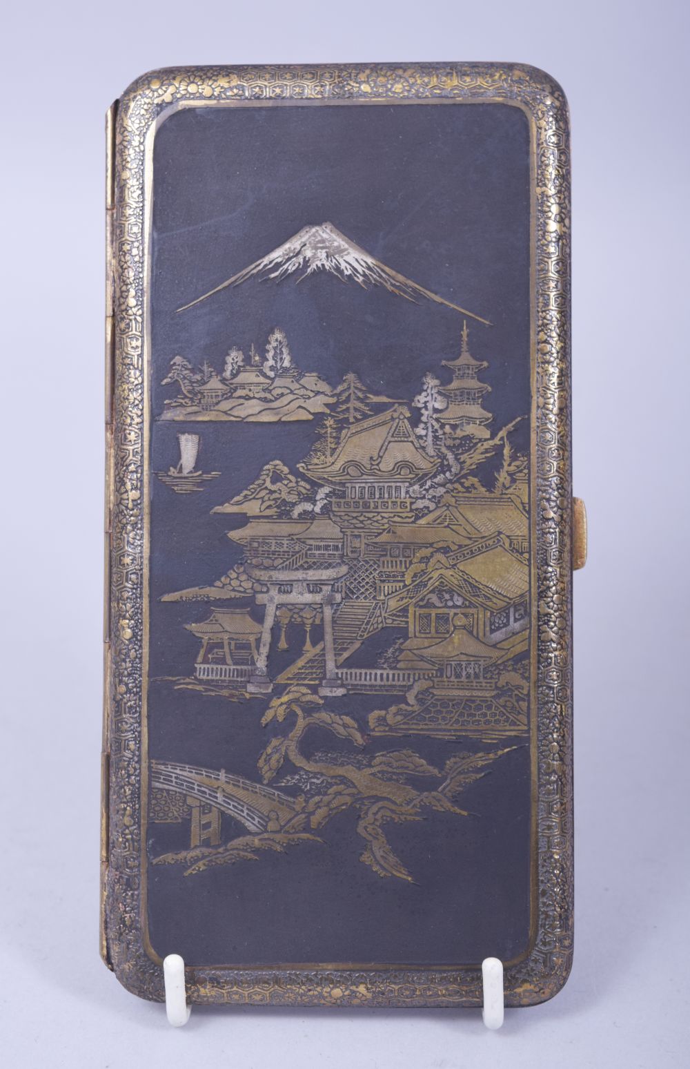 A JAPANESE DAMASCENED MIXED METAL CIGARETTE CASE, with a panel depicting buildings with mount fuji