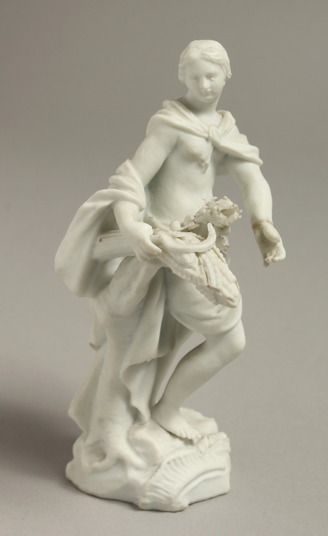 A LATE 18TH CENTRUY / EARLY 19TH CENTURY MEISSEN BISCUIT FIGURE of a girl with a scythe and a bundle