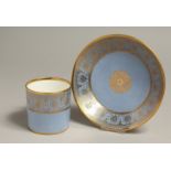 A SEVRES COFFEE CAN AND SAUCER decorated with elaborate classical gilding on a light blue ground.