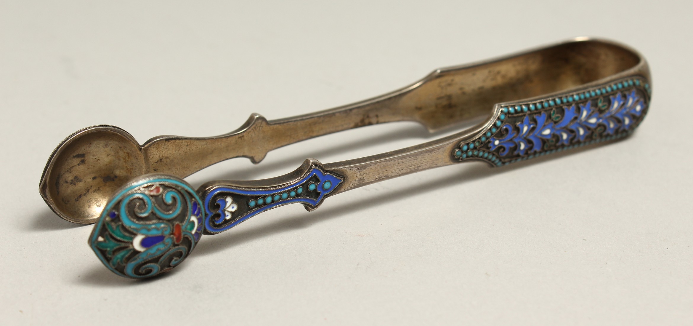 A PAIR OF SILVER AND BLUE ENAMEL SUGAR TONGS.