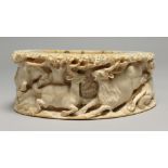A MAMMOTH CARVED BONE OVAL DISC, carved with deer and tiger. 5.25ins x 4.25ins x 1.75ins.