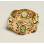 A 14CT GOLD PERIDOT BAND RING.