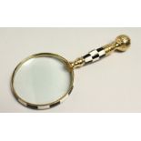 A MAGNIFYING GLASS WITH CHECKERED AND BRASS HANDLE.
