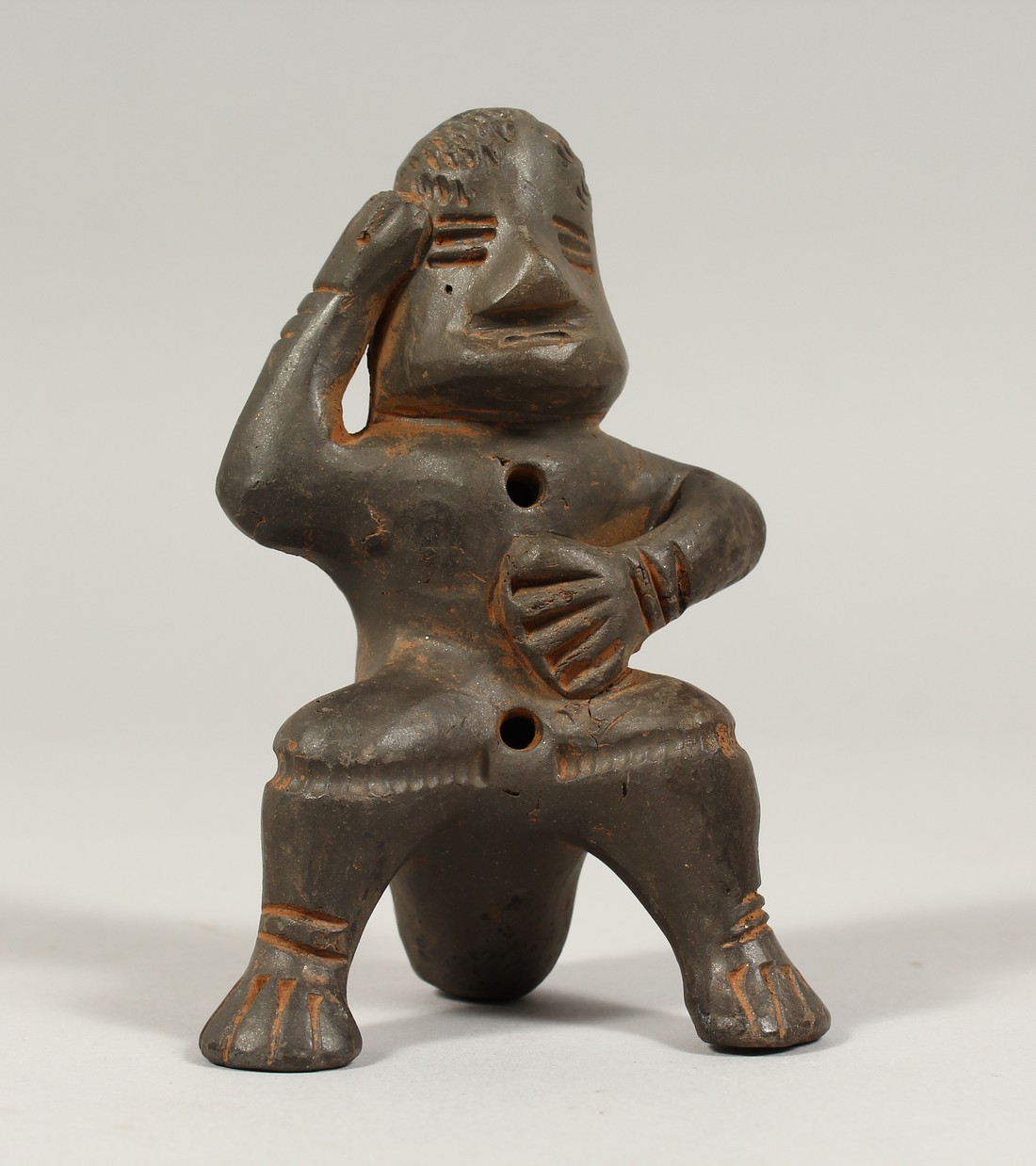 A SOUTH AMERICAN POTTERY WHISTLE as a seated figure,possibly from Peru. 4ins long