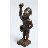 A CARVED WOOD TRIBAL FIGURE with glass eyes 7ins long
