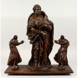 AN EARLY 17TH CENTURY CARVED WOOD SAINT holding a Bible and staff mounted on a wooden base with