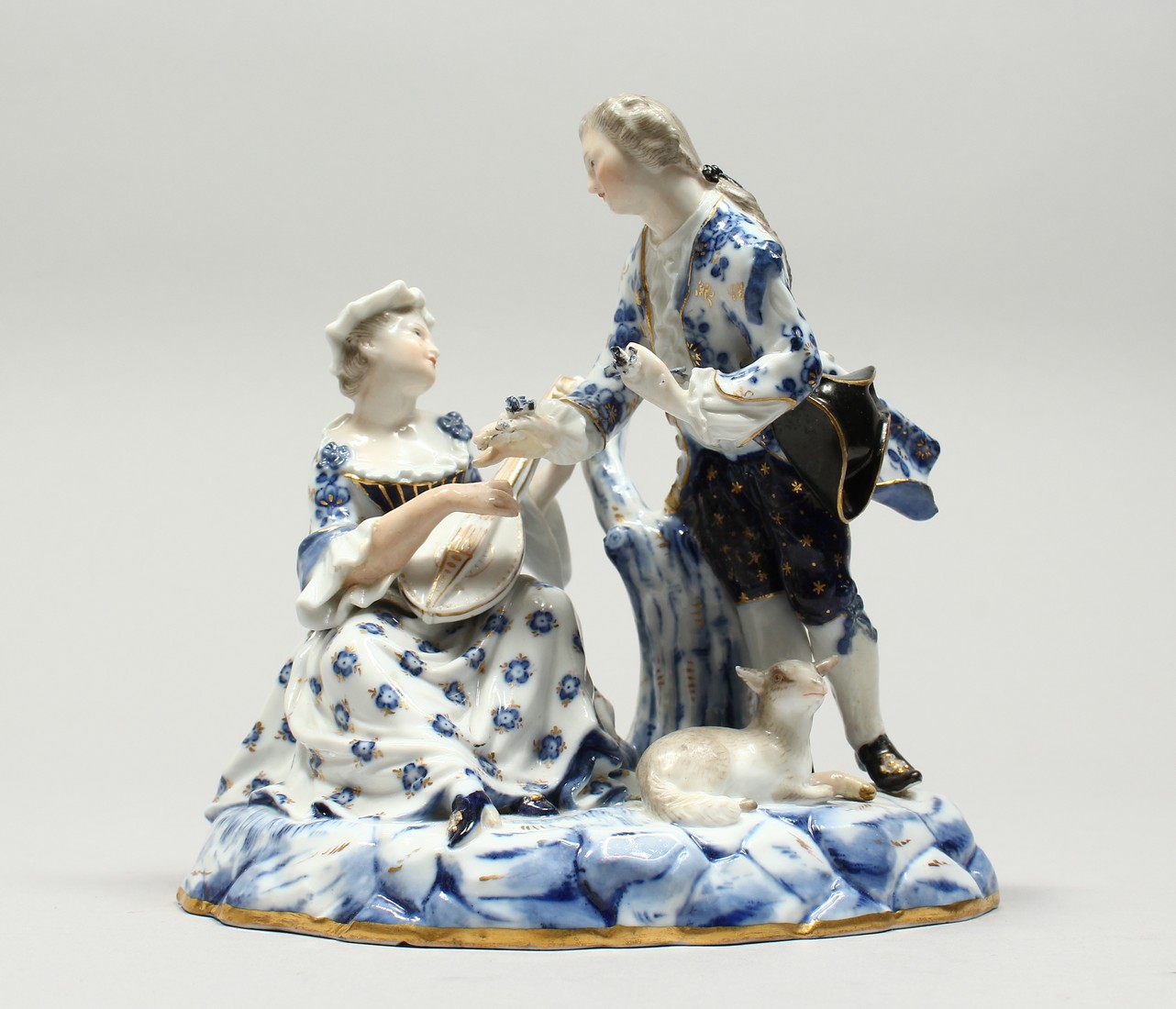 A GOOD MEISSEN PORCELAIN GROUP OF YOUNG LOVERS, a man with a lamb at his feet, a seated lady playing