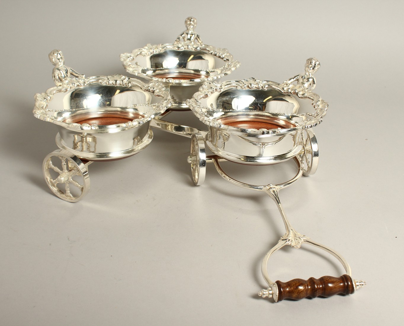 A SET OF THREE SILVER PLATED WINE COASTER in a case.