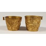AFTER THE ANTIQUE. A PAIR OF GREEK TWO HANDLED GILT CUPS. 4ins diameter.