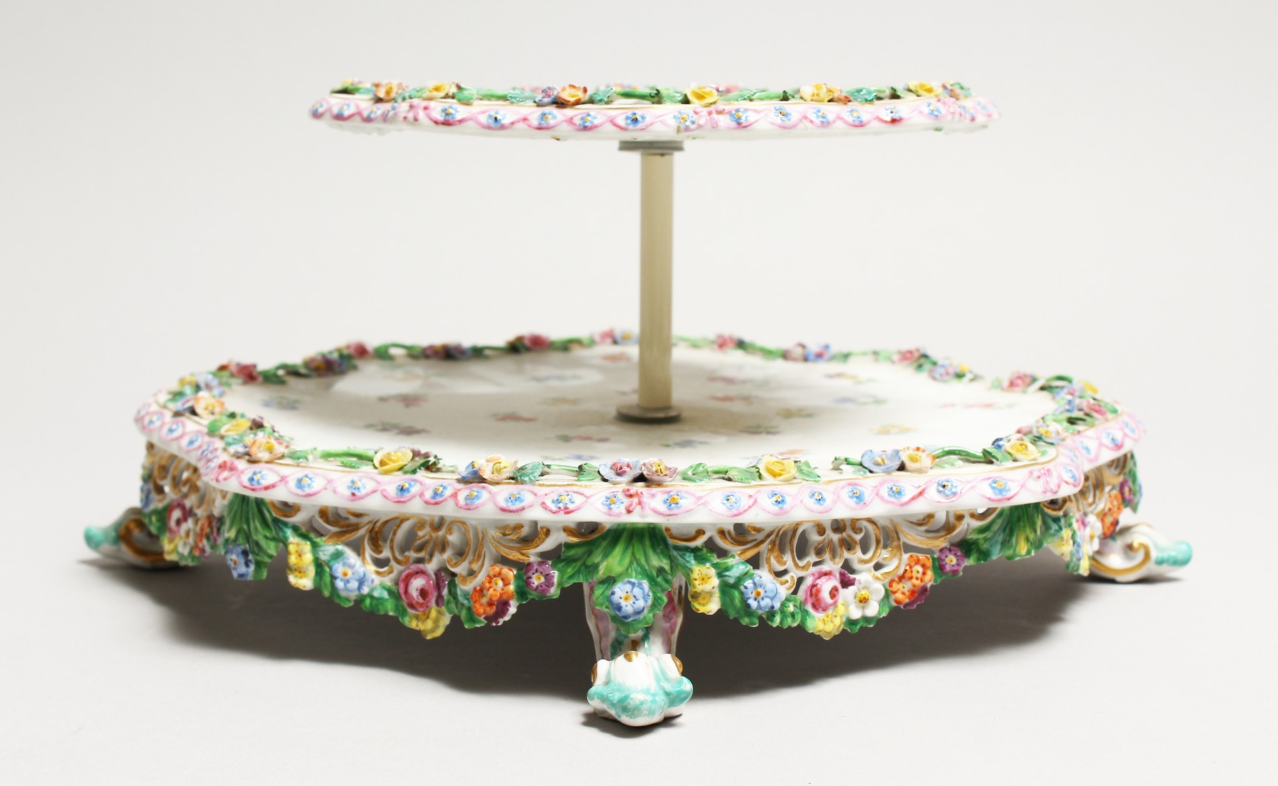 A 19TH CENTURY MEISSEN PORCELAIN TWO TIER STAND painted with roses and encrusted with flowers. Cross