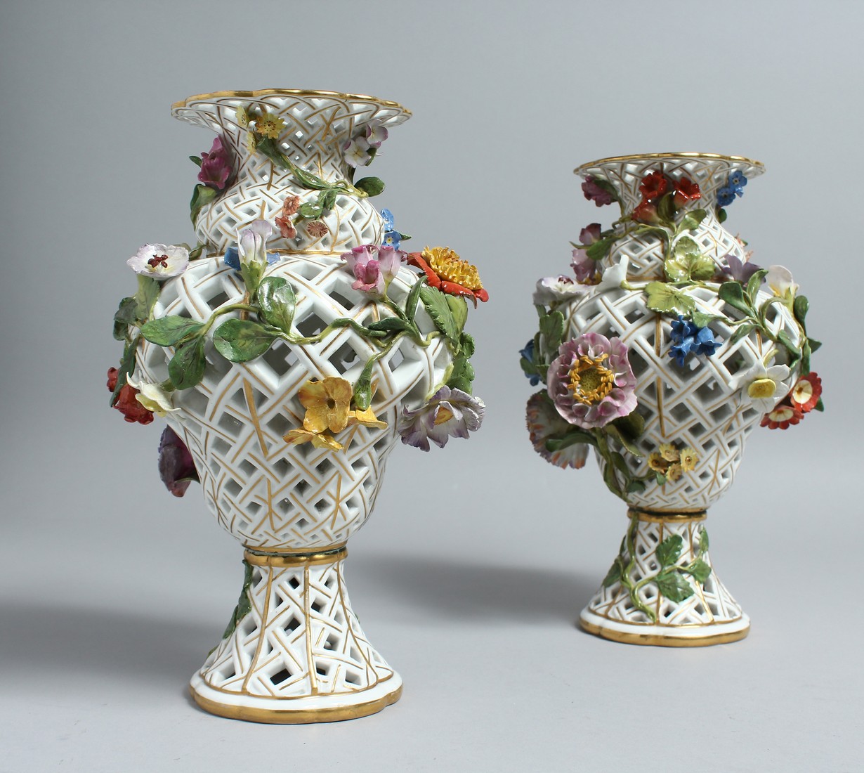 A PAIR OF MEISSEN PORCELAIN BALLUSTER SHAPED VASES, with pierced bodies and floral encrusted