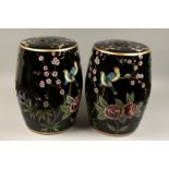A PAIR OF CHINESE BLACK PORCELAIN BARREL SEATS flowers and birds. 18ins high.