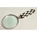 A MAGNIFYING GLASS WITH CHECKERED HANDLE.