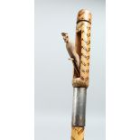 AN EROTIC BAMBOO WALKING CANE, the handle with a pop-out sailor - the shaft with burnt decoration.