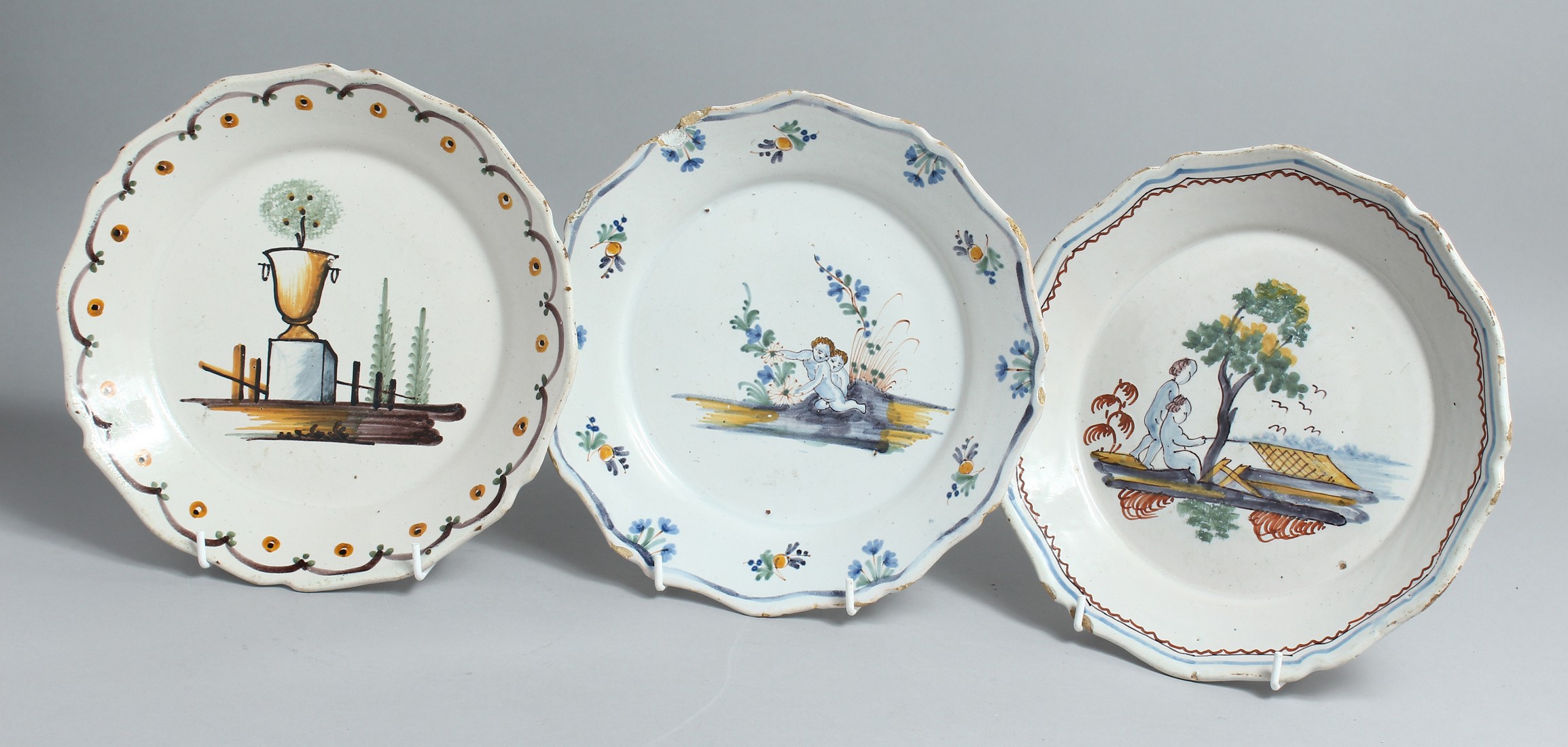 THREE 18TH CENTURY FAIENCE PLATES two with chickens, one with an urn. 8ins diameter.