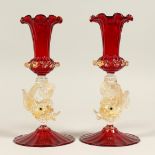 A PAIR OF VENETIAN RUBY TINTD GLASS VASES with dolphins stems. 9.5ins high.