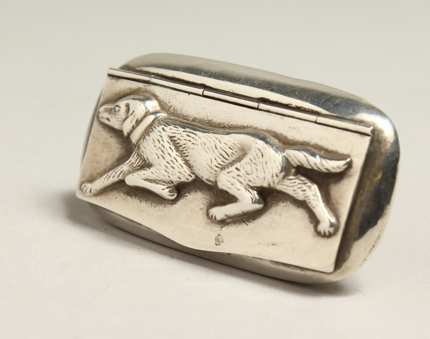 A SILVER SNUFFF BOX the lid fitted with a dog in relief. 2.25ins long.