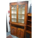 A 19th century fruitwood standing corner cabinet with a pair of glazed doors over a pair of panel