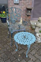 A cast metal garden armchair and small table.