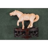 A carving of a horse on stand.