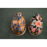 Two painted papier mache eggs on stands.