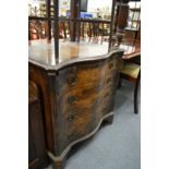 A serpentine fronted walnut chest of drawers with brushing slide.