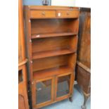 A mahogany bookshelf with two small drawers and a pair of glazed doors.