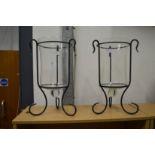 A pair of glass and wrought iron storm lanterns.