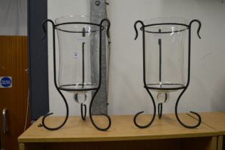 A pair of glass and wrought iron storm lanterns.