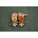 A silver brilliant set brooch of two birds on a branch.