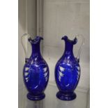 A pair of painted blue glass ewers.