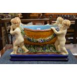 A Majolica style jardiniere modelled as a basket being held by four cherubs.