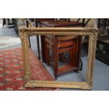 A giltwood picture frame and a picture of a young girl reading a book.