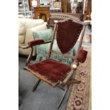 A Victorian mahogany and velvet upholstered folding armchair.