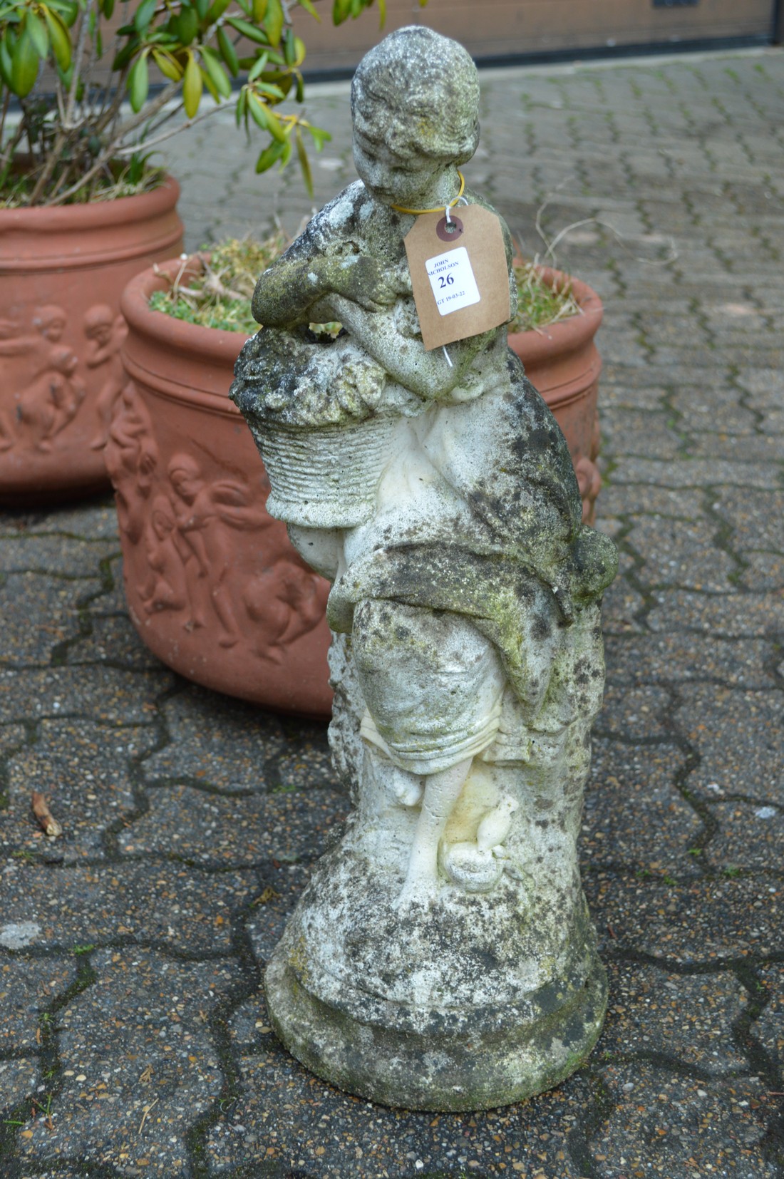 A small composite garden ornament modelled as a young lady holding a basket.