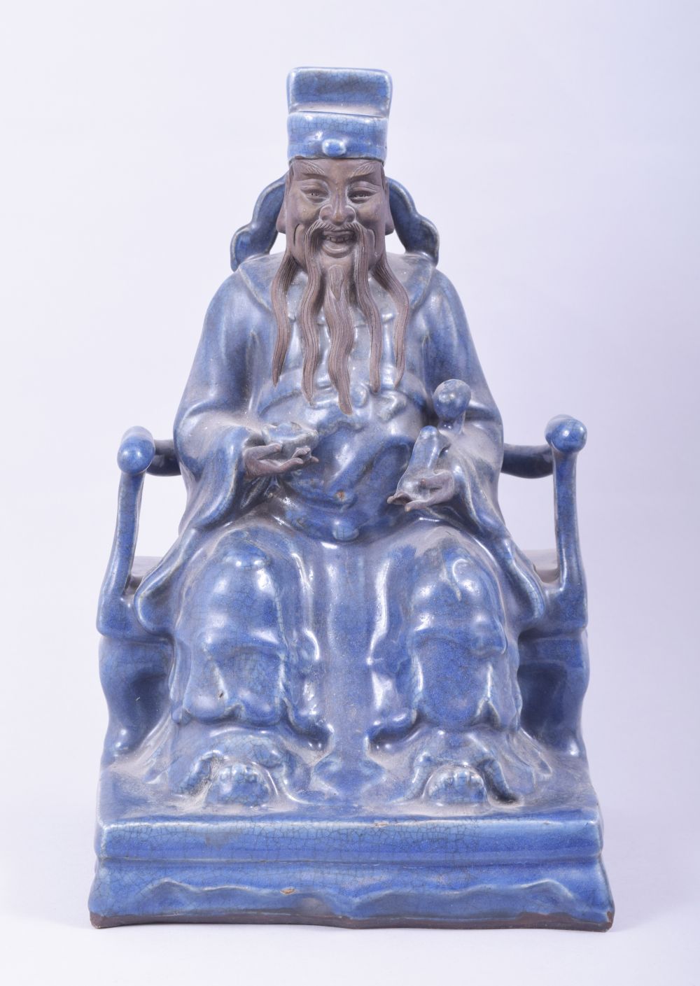 A LARGE CHINESE POWDER BLUE GLAZE POTTERY SEATED FIGURE of a god, the figure seated upon a throne