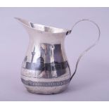 AN IRAQI SILVER AND NIELLO MILK JUG, decorated with river scene, 10cm high.