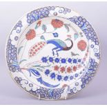A TURKISH OTTOMAN IZNIK POTTERY DISH, the centre painted with a peacock and flora, 31cm diameter.