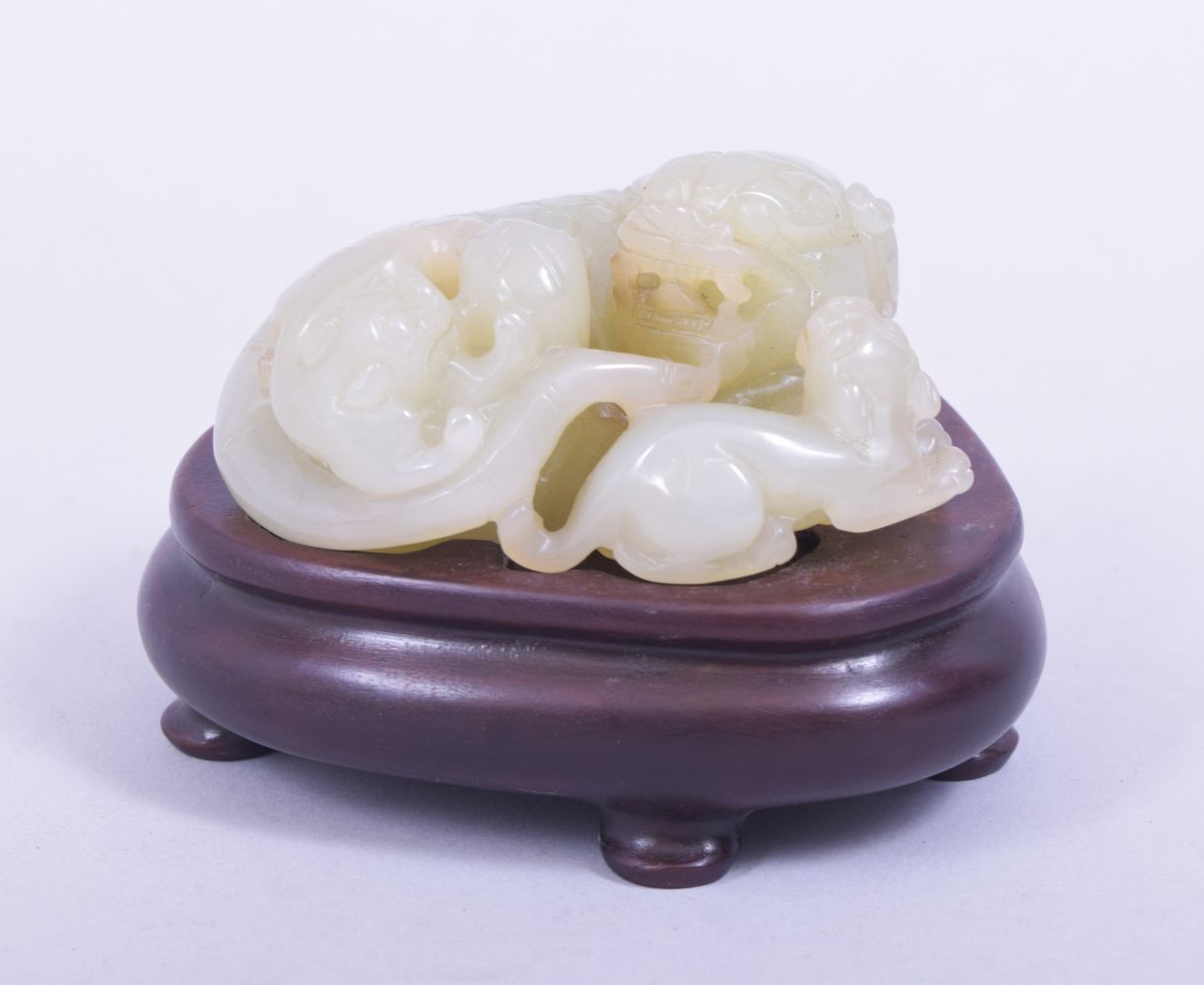 A CHINESE QING DYNASTY CELADON JADE CARVED THREE LIONS, on a fitted hardwood stand, jade 9cm x 8.