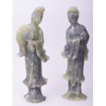 A PAIR OF CHINESE CARVED JADE STANDING FEMALE FIGURES, one carved holding a peach, the other holding